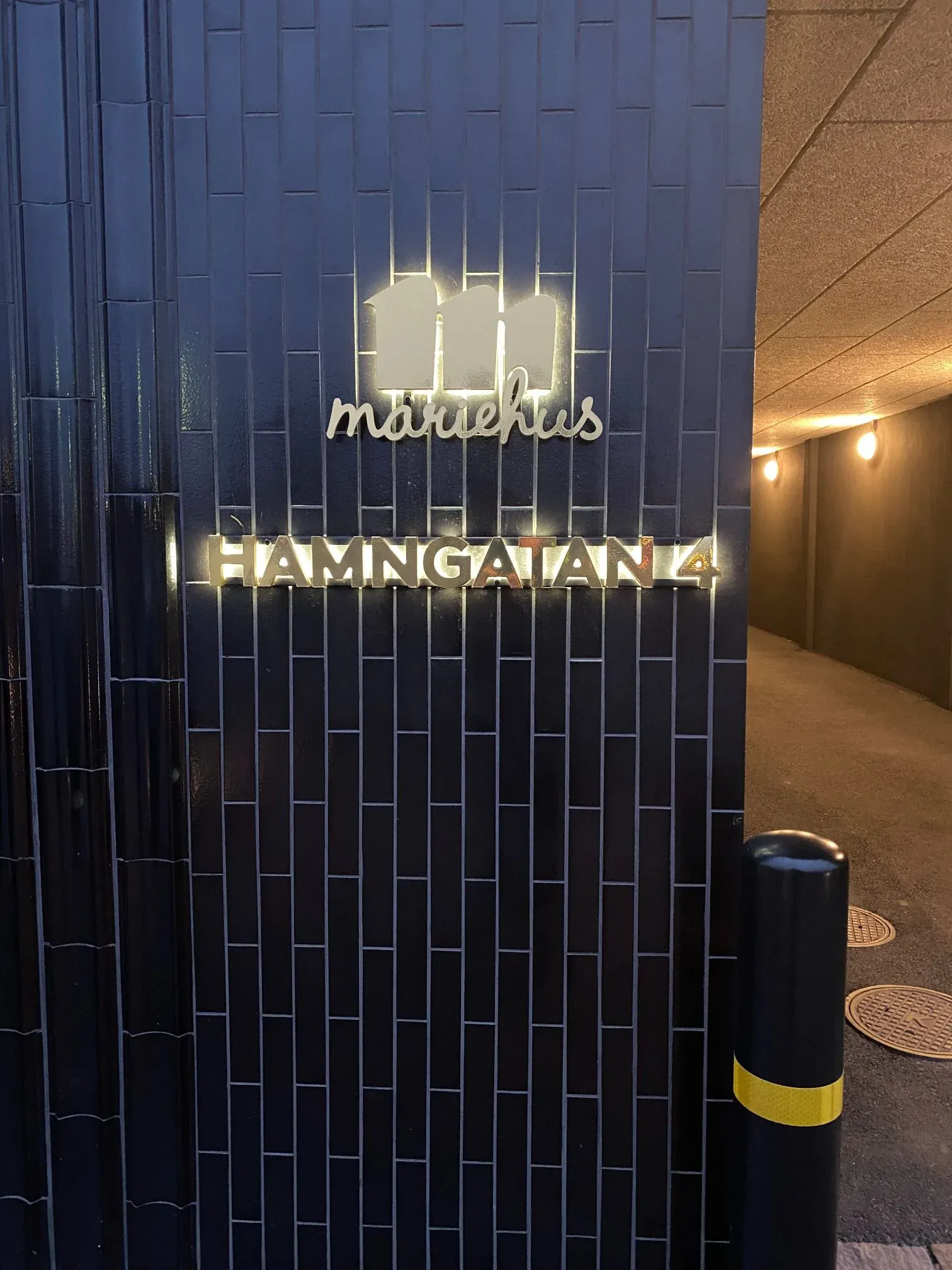 Mariehus ljusskylt på Hamngatan, monterad på mörk tegelfasad